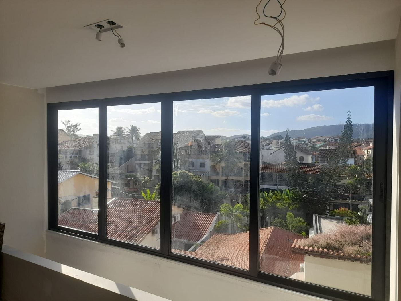 Janela de alumínio preta de quatro folhas com vista para o bairro