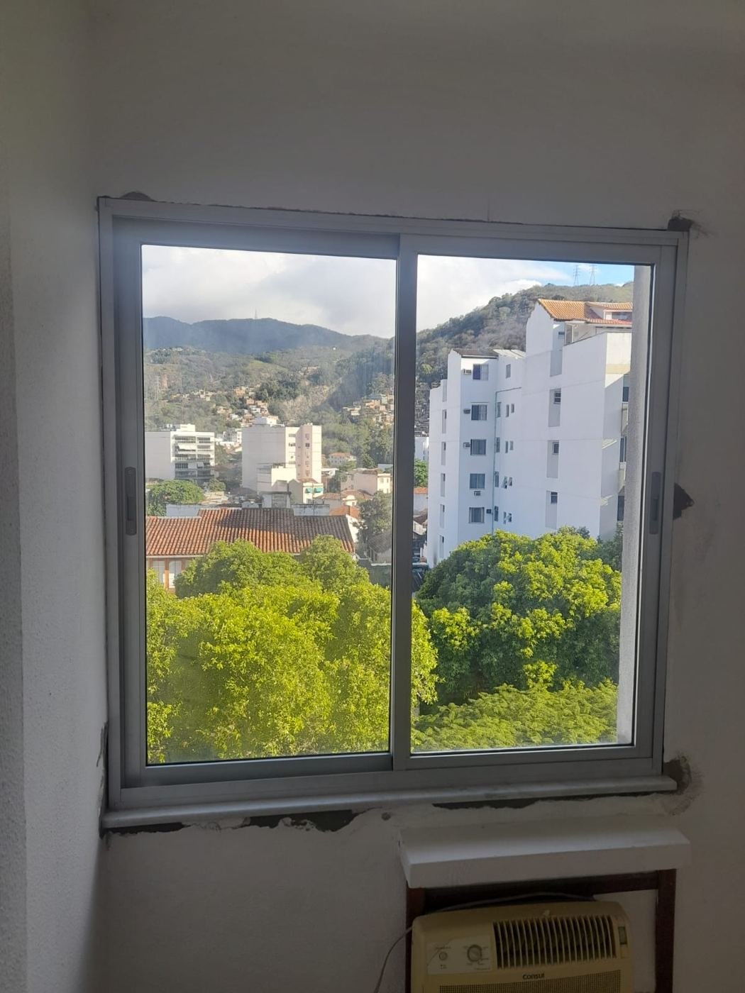 Janela de correr branca com vista para o morro