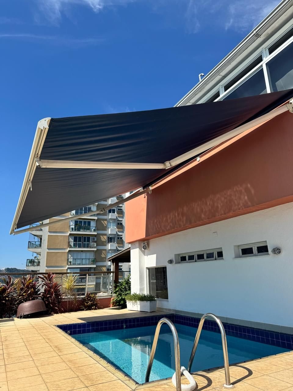 Toldo retrátil escuro sobre a piscina na cobertura de um prédio